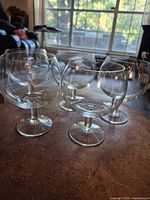 Five clear glass snifters on tabletop