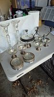 Group shot showing all items: glass candlesticks, dessert cups, coasters, lidded dish, candelabras
