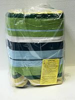 Folded Outsunny fabric hammock in plastic wrap showing green, blue, white, and yellow stripes along with caution label.