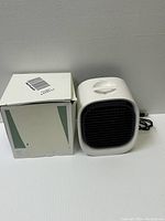 White portable air cooler fan with original box beside it, showing the compact design and packaging.
