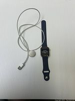 Apple Watch Series 4 with blue sport band lying flat with USB charging cable next to it, screen on with text message.