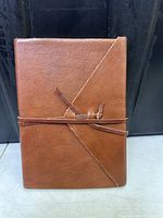 Brown leather journal with wrap tie closure, viewed from front.