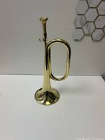 Side view of shiny brass bugle with single tubing loop and flared bell.