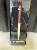 Photo of Gry Mattr ball point pen in packaging showing wood-textured brown upper barrel and white lower barrel, unopened.