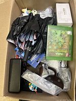 Top-down view showing umbrellas, NBA board game, black solar lights, and kitchen mitts inside cardboard box