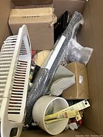 Full view of the box showing various household and miscellaneous items including crate, wallet, wrapped tool, bowls, and packages.