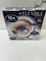 Box front showing product name, features such as 10x magnification, LED illumination, touch sensor, and suction mount with an eye close-up image.