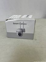 Front of retail box showing white smart camera image with antenna and lens surrounded by infrared LEDs.