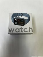Photo of boxed smart watch showing blue silicone band and 'watch' printed on box front.
