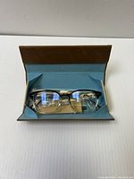 Pair of Toms optical glasses in black and clear frame inside original case with light blue interior and brown lid.