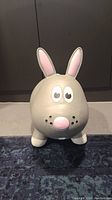 Front view of gray inflatable bunny hopper toy showing eyes, pink ears, nose, and whisker dots