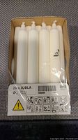 Box of 20 IKEA Jubla white taper candles in original packaging, showing label and warning icons.