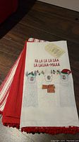 Photo showing the white towel with three llamas in holiday attire and text 'FA LA LA LA LAAA LA LALAA-MAAA' with tags attached