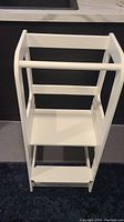 Front view of white solid wood toddler educational tower with adjustable platform