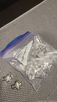 Plastic bag containing multiple crystal knobs with metal fittings, some knobs laid out on textured surface.