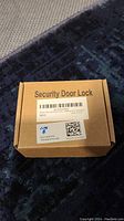 Closed cardboard box labeled 'Security Door Lock' with barcode and QR code.