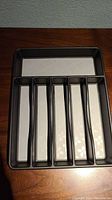 Black metal cutlery tray with six compartments for utensils