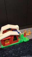 Red and white Little People barn house with green base, scarecrow figure, dog, and fence