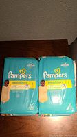 Two packs of Pampers Swaddlers diapers size 1 with 32 diapers each, new and sealed.