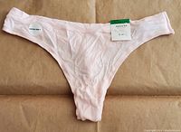 Front side of light pink Alfani medium size elastic underwear showing the front and a circular 'Ultra Soft' sticker along with brand tag and price tag.