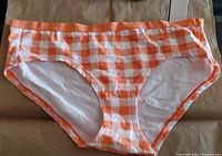 Front view of orange and white gingham checkered bikini style underwear showing the pattern, waistband and cut.