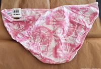 Top side view of the pink tie-dye bikini bottom with tags showing brand and size.