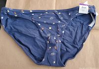 Front view of navy bikini bottom with peace sign toss and whimsical print, showing attached size tag and brand label.