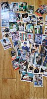 Photo showing a collection of approx. 30 baseball cards laid out on wooden floor, mostly newer cards featuring Rockies players and others.