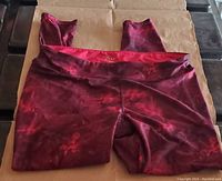 Front view of red marbled yoga pants laid flat showing wide waistband and marbled pattern.