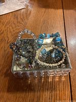 Top-down view showing multiple stretchy bracelets stored in a small mirrored jewelry box with a crystal-like exterior.