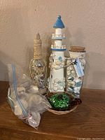Full lot showing lighthouse, jar with seashells, plastic bag with loose shells and glass sea turtle figurine