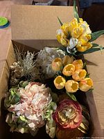 Box with assorted artificial flowers including different varieties and colors seen from above