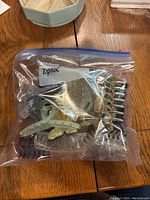 Photo of a plastic zipper bag containing various hair clips of different sizes and colors including clear, brown, and silver.