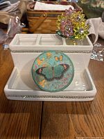 Front angle of the white ceramic brush holder with rhinestone trim and butterfly soap box in front