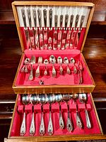 Complete view of the two-drawer wooden chest open showing knives, forks, spoons arranged in red felt lining.