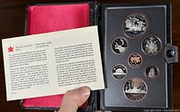 Image of proof coin set inside protective black case with red lining, includes informational leaflet from Royal Canadian Mint in English and French.
