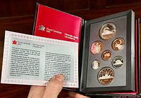 Open folio case displaying seven proof coins set in foam mounts with certificate booklet.