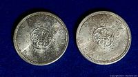 Two 1964 Canadian silver dollar coins showing the reverse side with floral emblems and inscriptions.