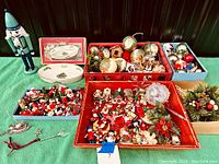 Overview of assortment showing multiple trays of Christmas ornaments including glass balls, wooden figures, and decorations alongside a large wooden nutcracker figure.