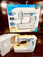 Euro-Pro X-32 sewing machine in original box with cover, showing front and side profile.