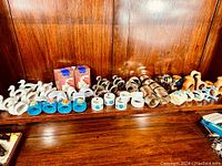 Wide view of collection showing various napkin rings made from porcelain, plastic, metal, and wood spread on wooden surface.