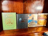 Four Nintendo gaming books and guides displayed on a wooden shelf.