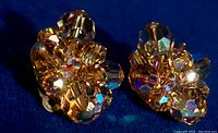 Close-up photo of one earring showing yellow topaz and Aurora Borealis faceted rhinestones in a cluster floral design with clip-on backing.