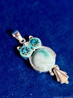 Close-up front photo of owl pendant showing Larimar body, blue stone eyes, and silver detailing.