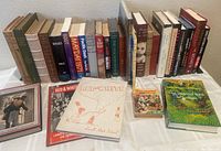 Photo showing a collection of hardcover books and several Lowell High School yearbooks on a table, including 'One Hundred Years of Solitude' and 'The Orphan Brigade'. Books have colorful spines and visible titles.
