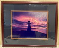 Frontal view of the framed signed photograph showing lighthouse silhouette during sunset with purple and orange sky.