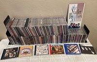 Wide view showing a large quantity of CDs stacked in rows including The Statler Brothers, The Beatles, Eagles, Led Zeppelin, and more.