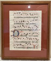 Full front view of framed manuscript leaf showing frame, matte and glass reflections