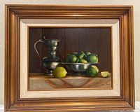 Full view of the framed oil painting showing the pewter pitcher and bowl with limes on a marble surface.