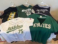 Photo showing eight sports T-shirts on hangers including Athletics, Raiders, and Marcus Semien shirts